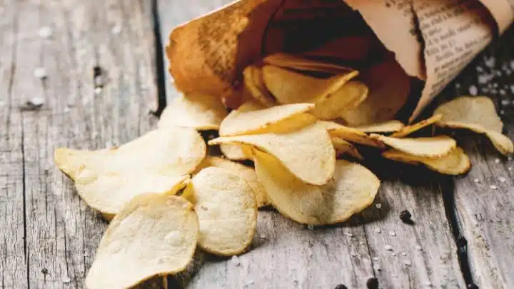  perfectly crisp potato chips wrapped in paper on wooden backdrop