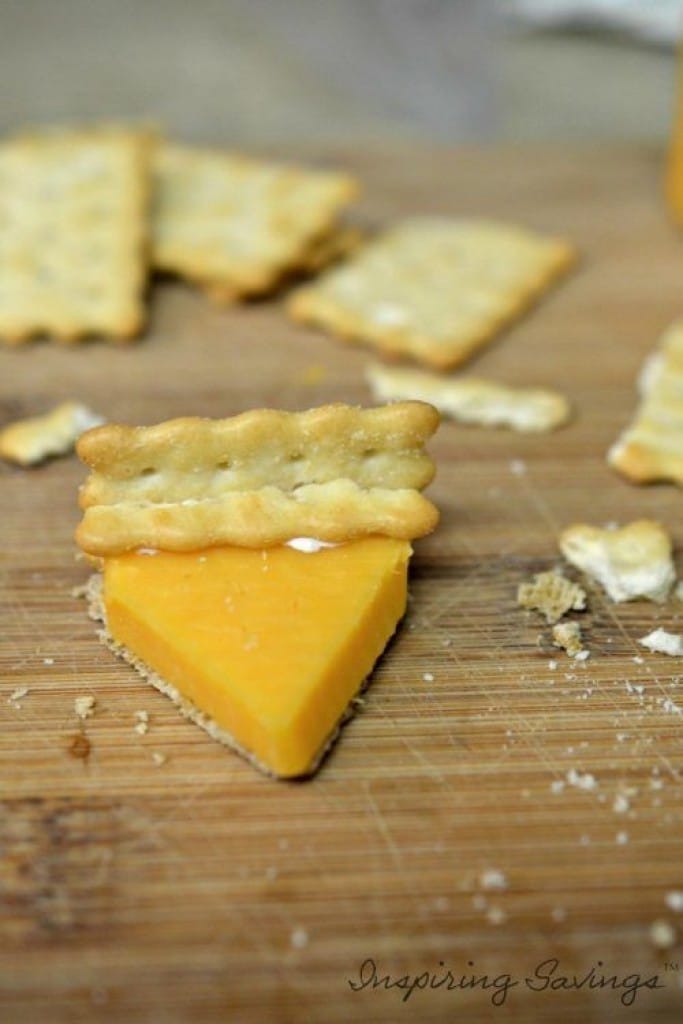 Making Mini Pumpkin Pies out of cheese & crackers on cutting baord