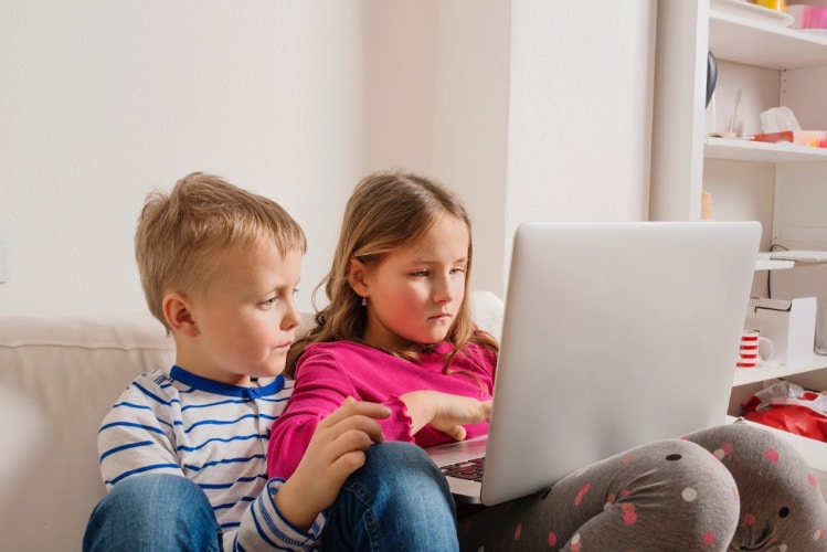 Little boy & girl sitting on couch with laptop - online learning websites