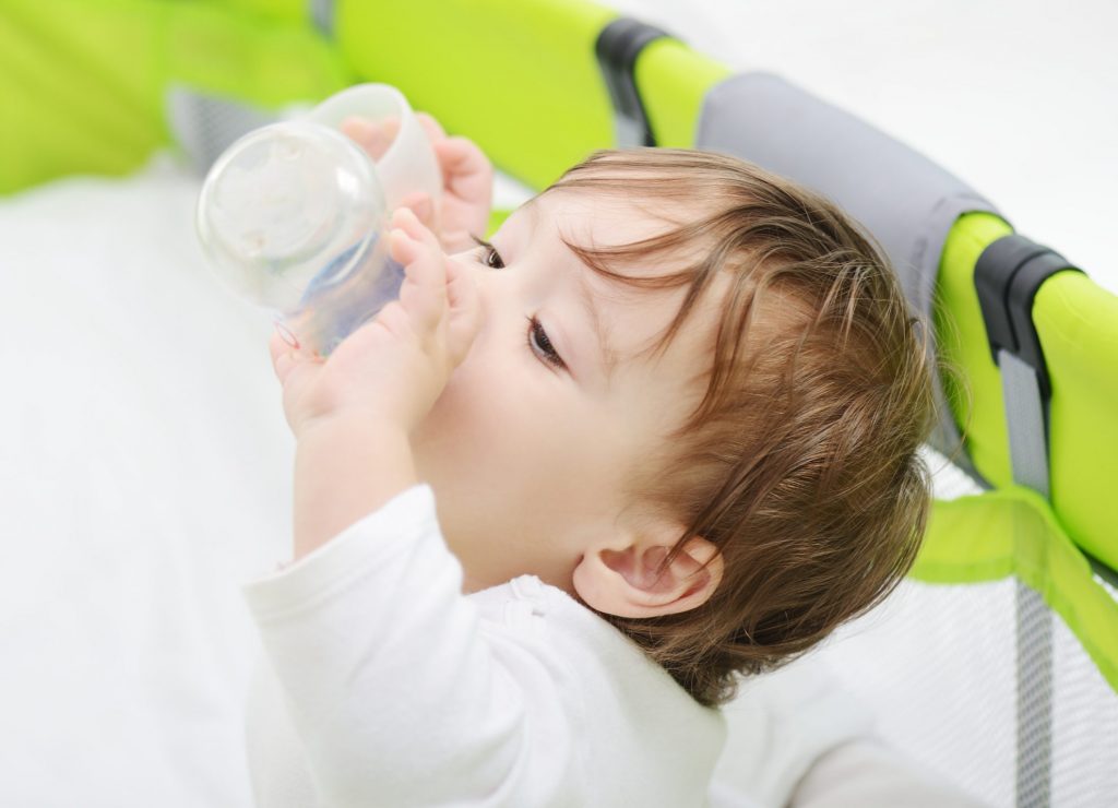 Infant in crib  drinking for a bottle