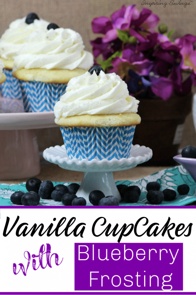 Vanilla Cupcakes with Blueberry Frosting on cake stand with purple flowers and loose blueberries