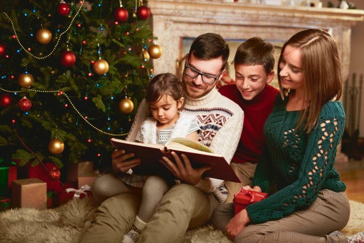Happy Family reading by christmas tree