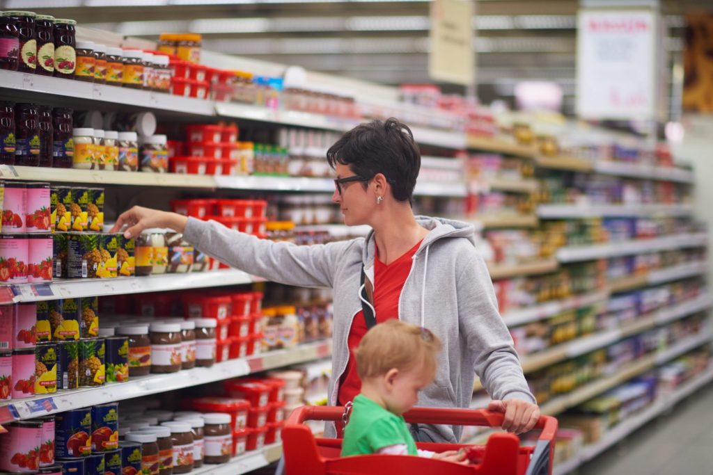 Woman shopping in grocery store with child - coupon lingo