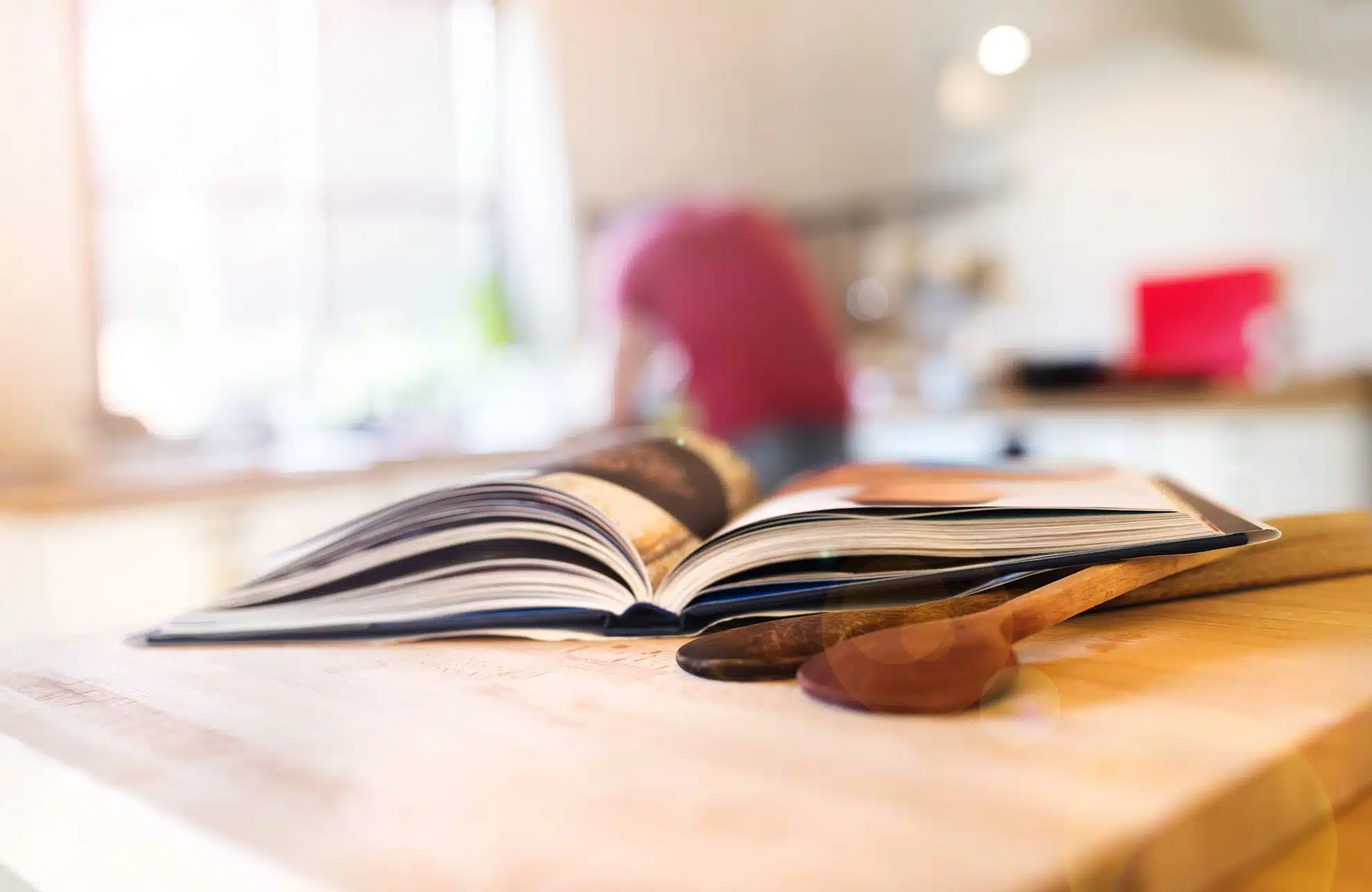 cookbook open with wooden spoons on kitchen island