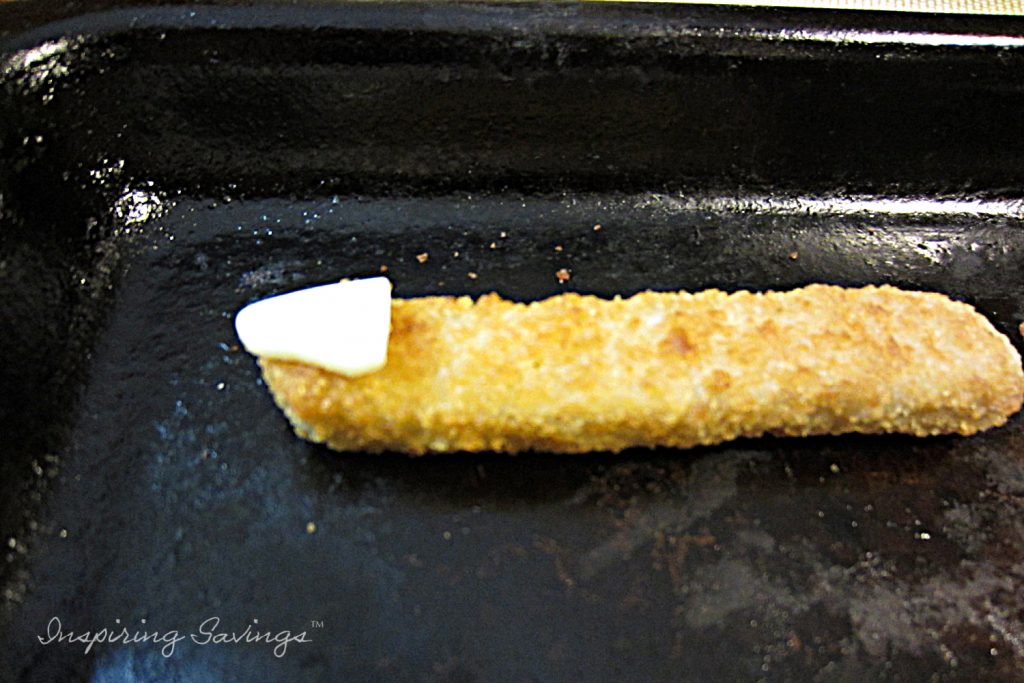 Cooking fish sticks. Added triangular piece of cheese.