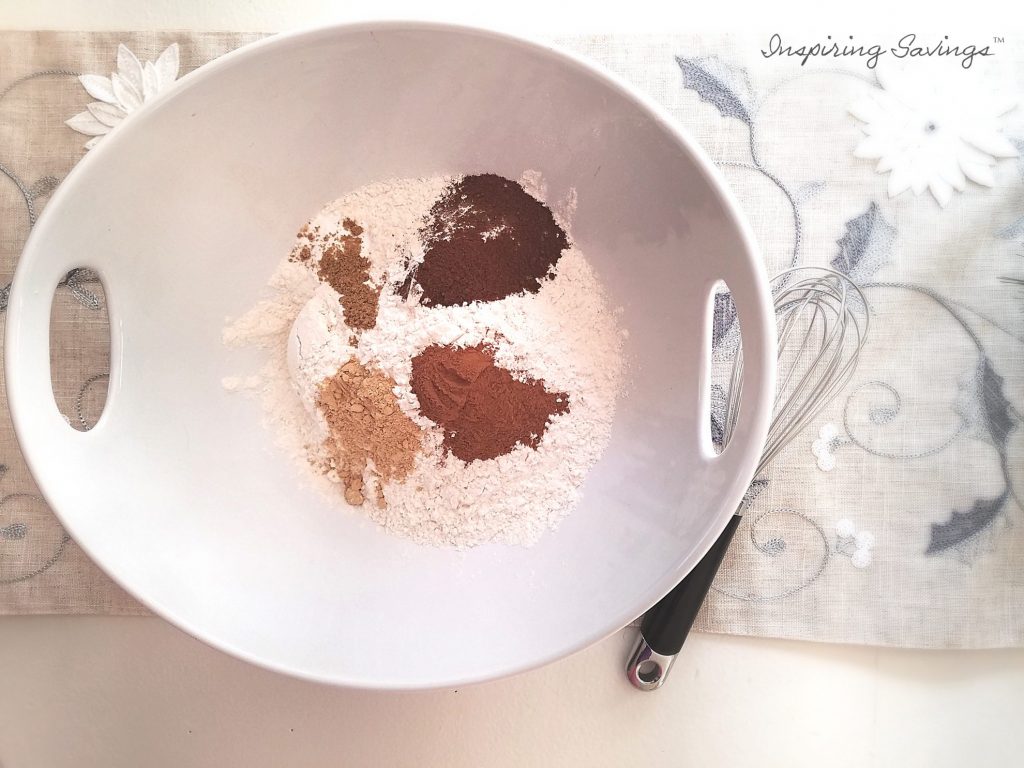 dry ingredients for gingerbread cookies in white bowl with whisk