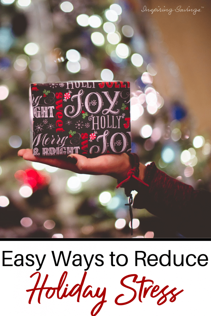 Woman holding package in front of Christmas tree - Easy ways to reduce stress