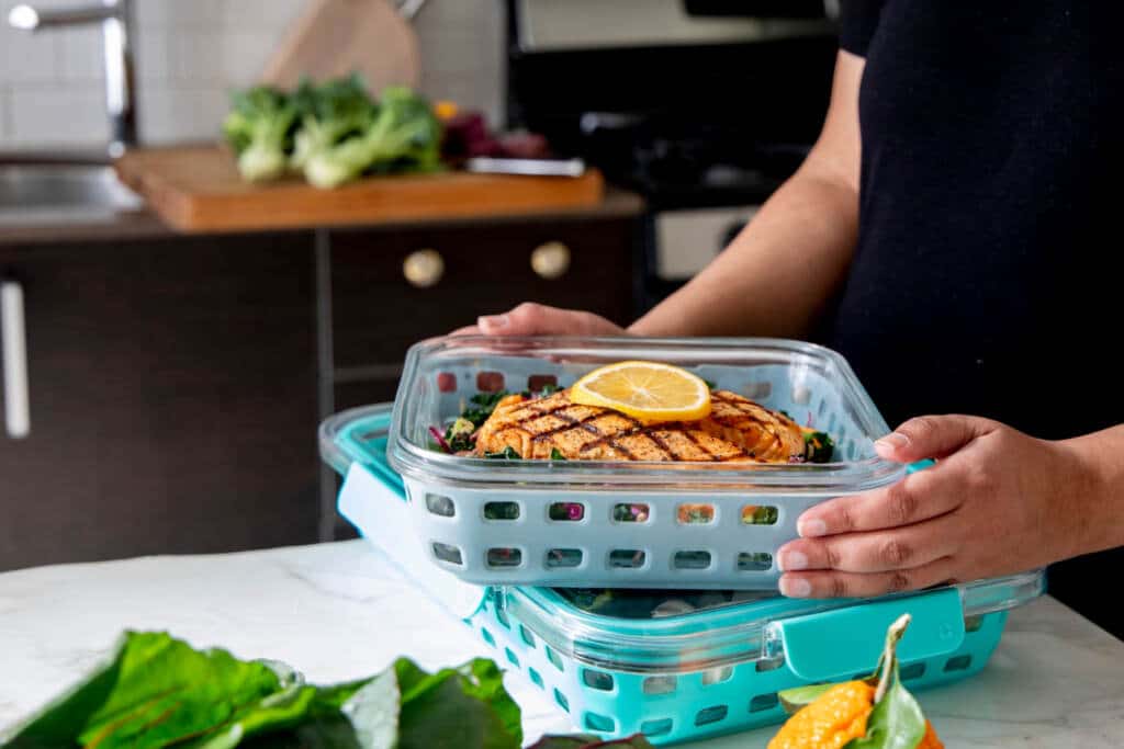Woman hold glass food containers on counter top for meal prep