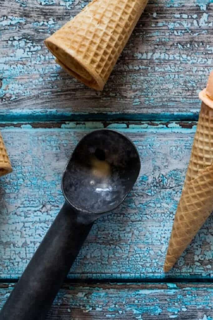 ice cream scooper on wooden blue background with ice cream cones