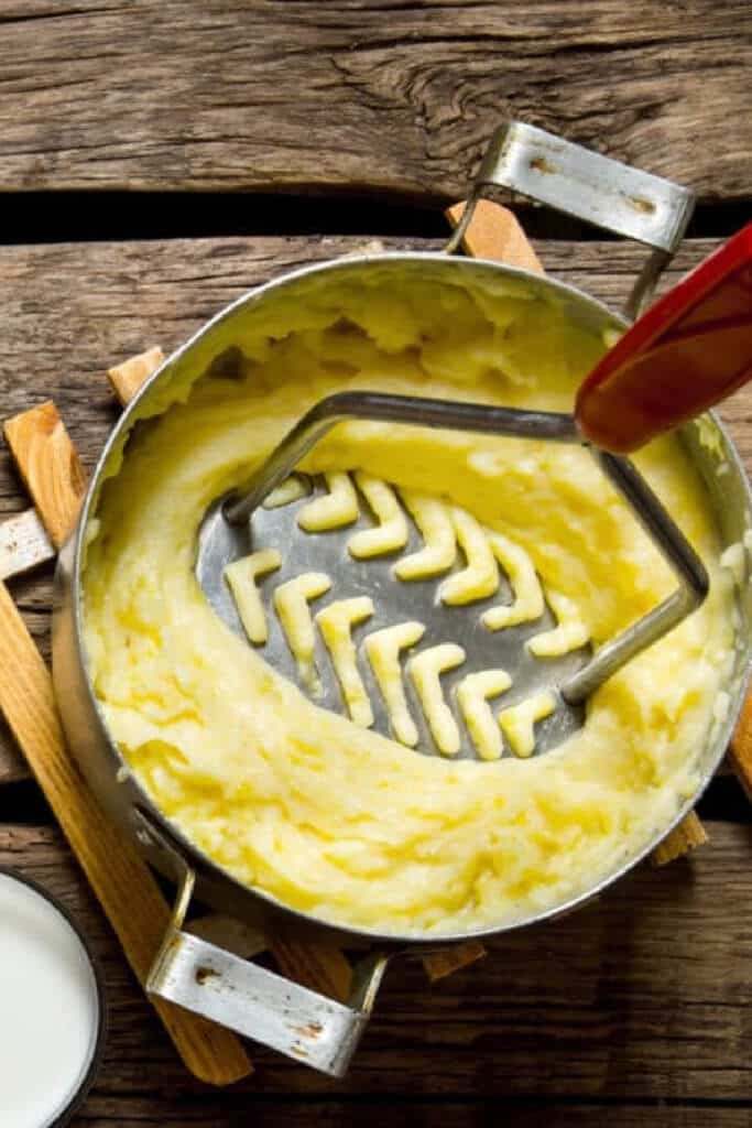 potato masher - mashing potatoes in metal pot