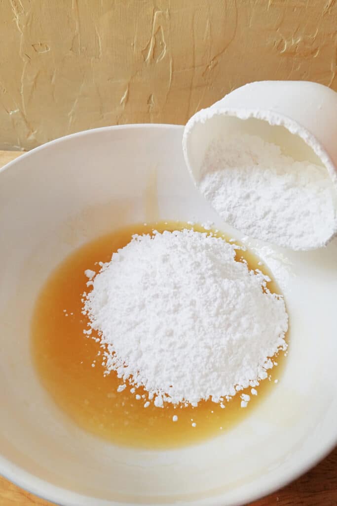 Adding powder sugar to honey mixture in bowl