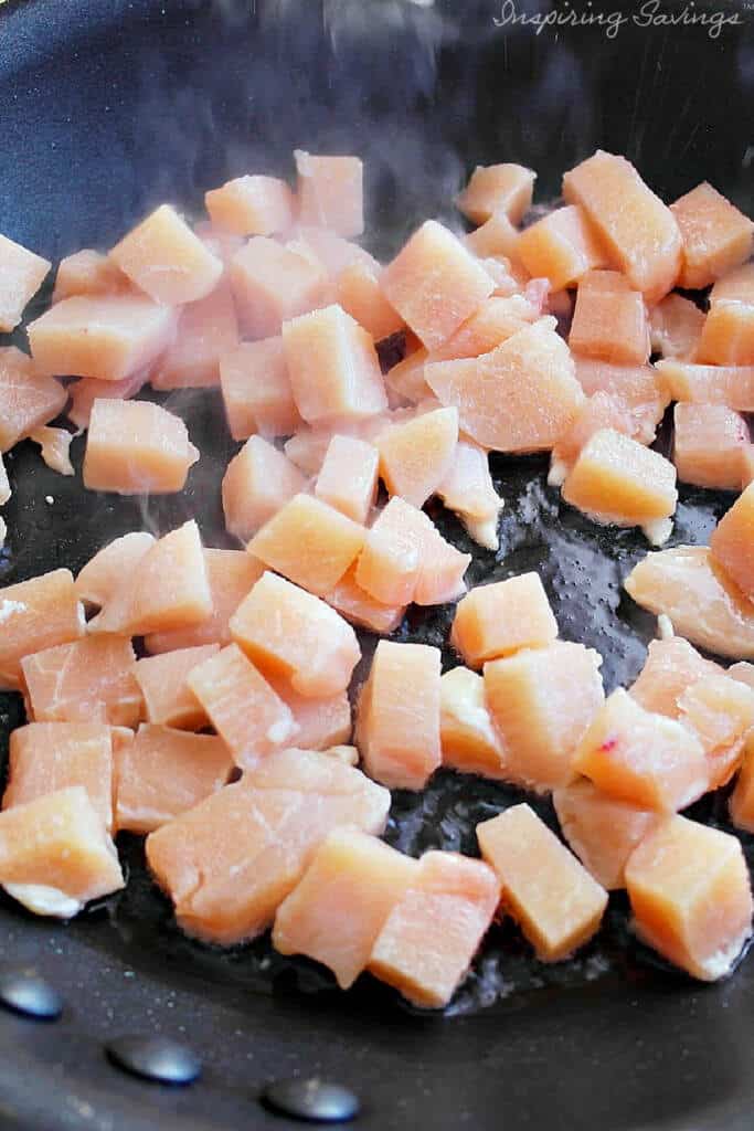 Cube sized pieces of chicken cooking in pan