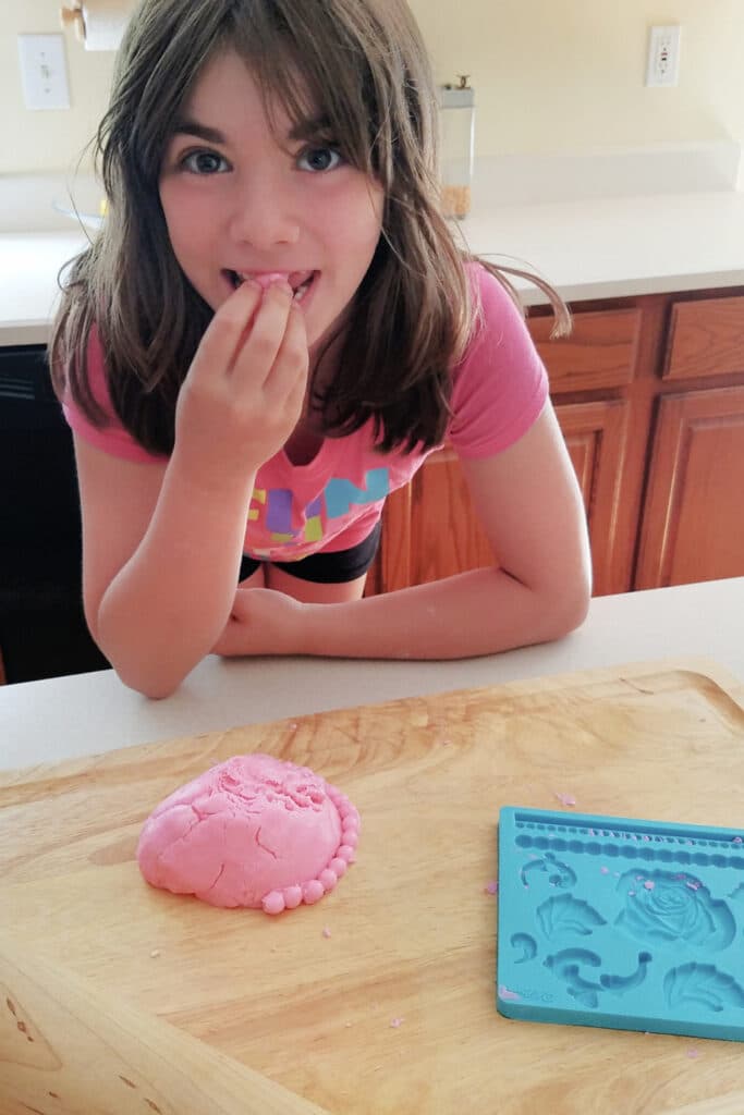 Little girl wearing pink eating Homemade Playdough - Classic recipes