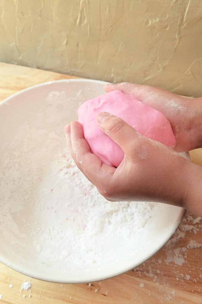 Pink Playdough made edible. Child's hand mixing play dough