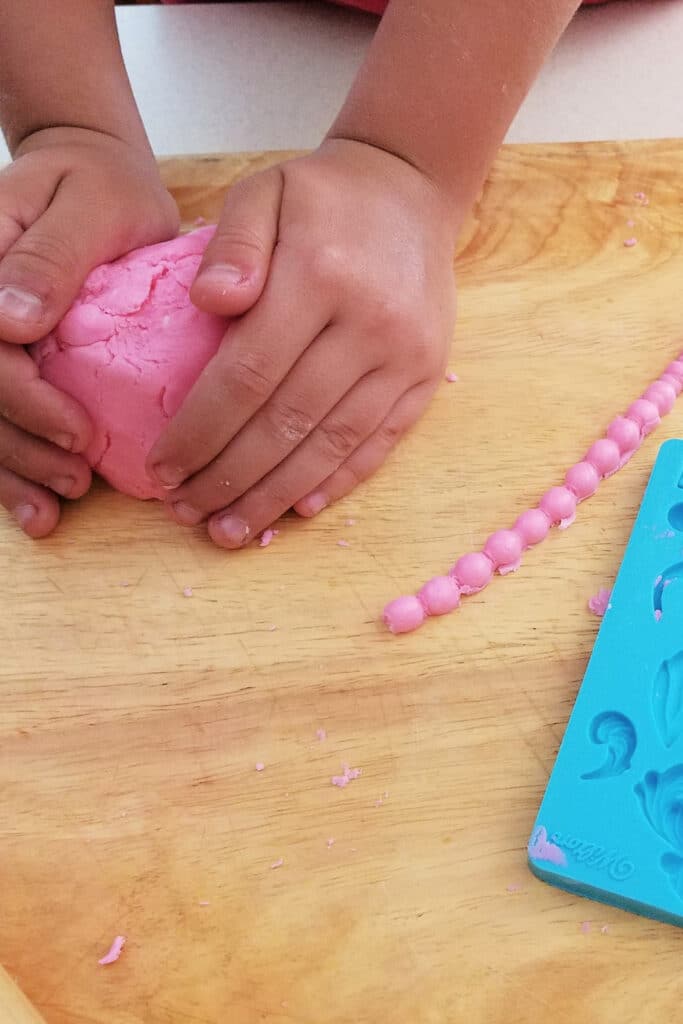 Playing with homemade play-doh on cutting board with toys