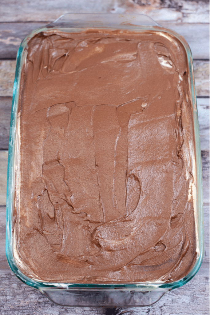 Putting frosting on cake in clear glass casserole dish