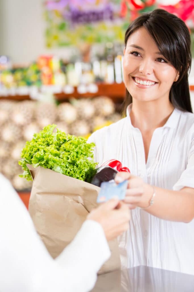 Woman checking out at register spending on groceries