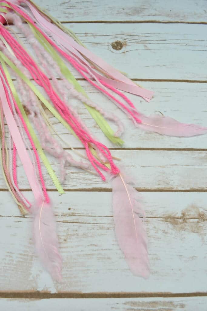 Adding feathers to tails of floral dream catcher craft
