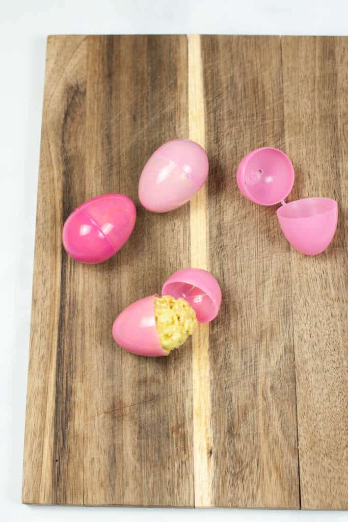 Adding rice krispies in egg molds on wooden background