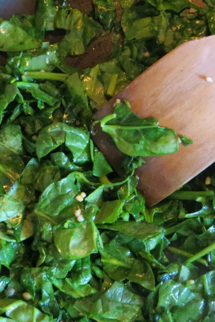 Cooking Spinach and cloves of garlic chopped in skillet