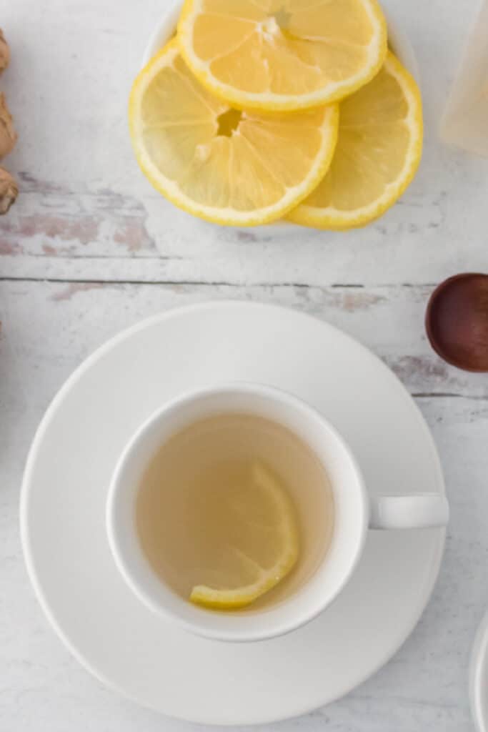 Ginger tea in white cup with slice of lemon white background