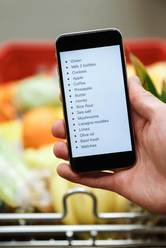 Making a grocery store list. Smart phone in hand with digital grocery list