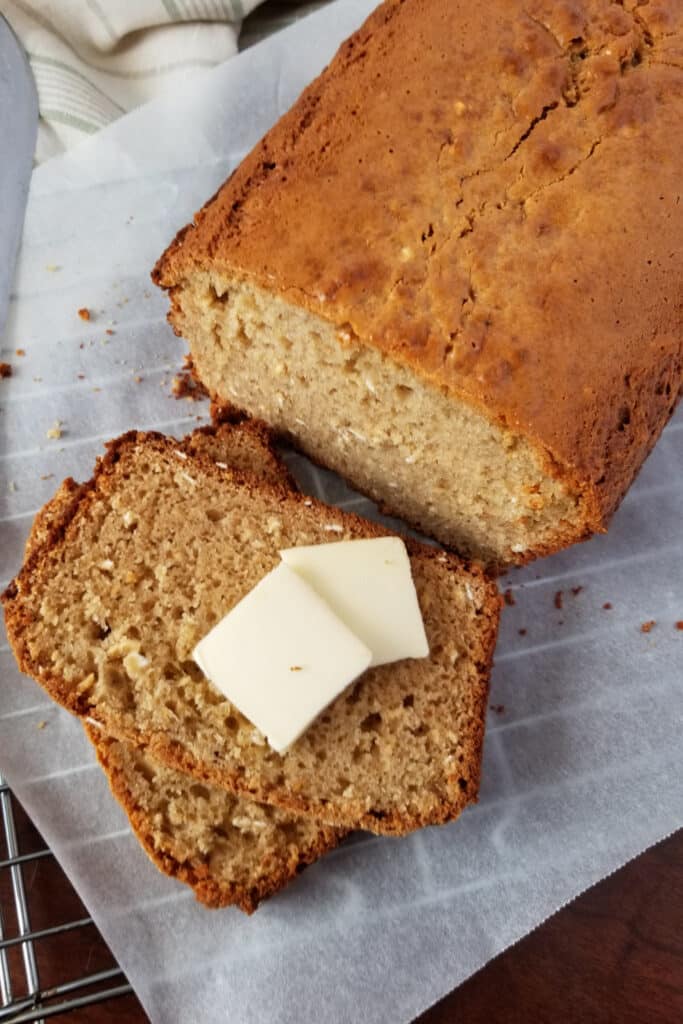 Peanut butter bread on cooling rack with two tabs of butter