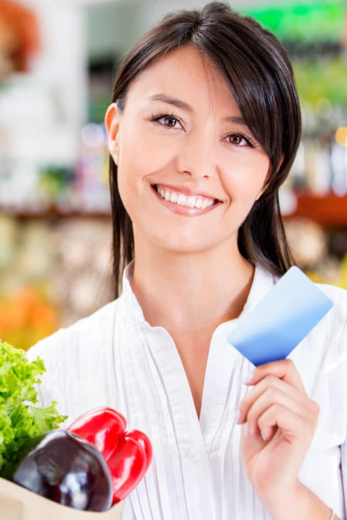 Using store loyalty cards - woman at checkout hold store loyalty card in hand
