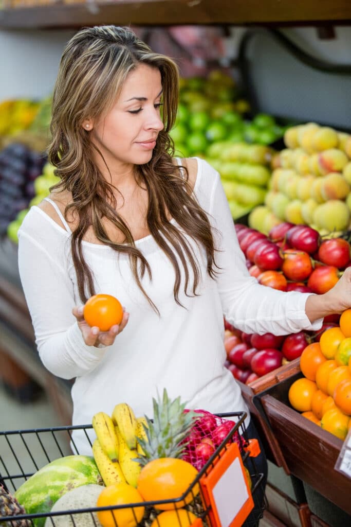 woman shopping in produce section avoiding supermarket spending traps