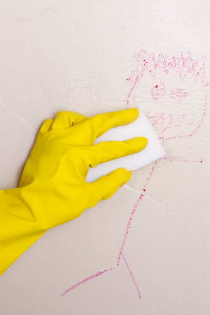 Cleaning crayon marks off wall with a with magic eraser