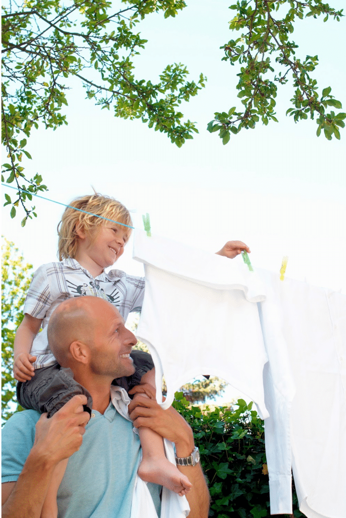 Line drying clothes - father and son putting clothes on a clothing line outside - fresh air