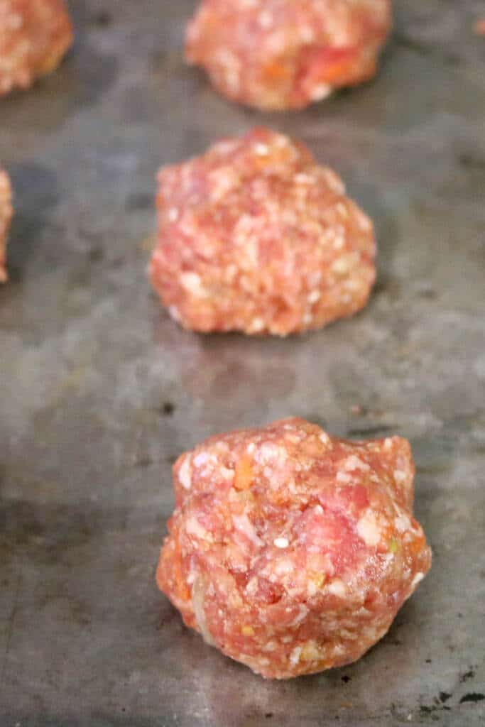 Rolling out ginger pork meatballs on baking sheet