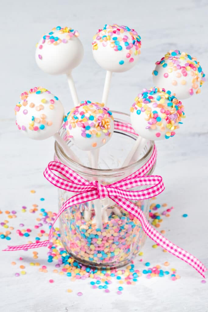 vanilla cheese cake pops in mason jar with sprinkles on white background