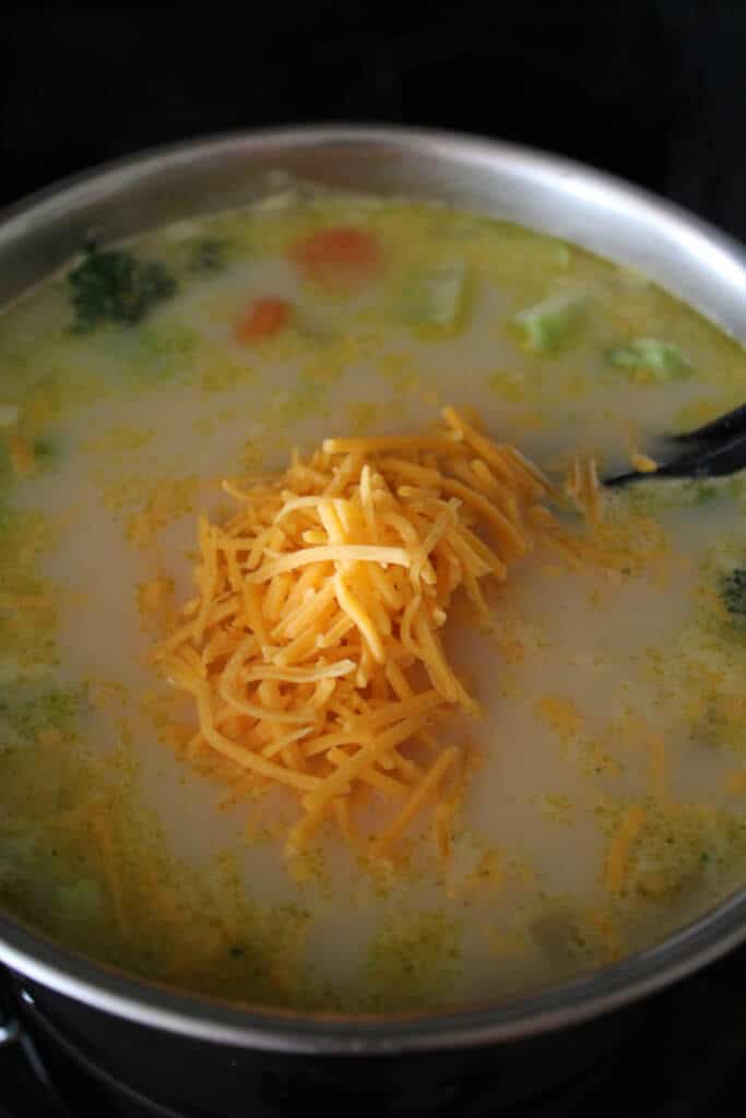 Adding cheese to vegetable Chowder in large sauce pan