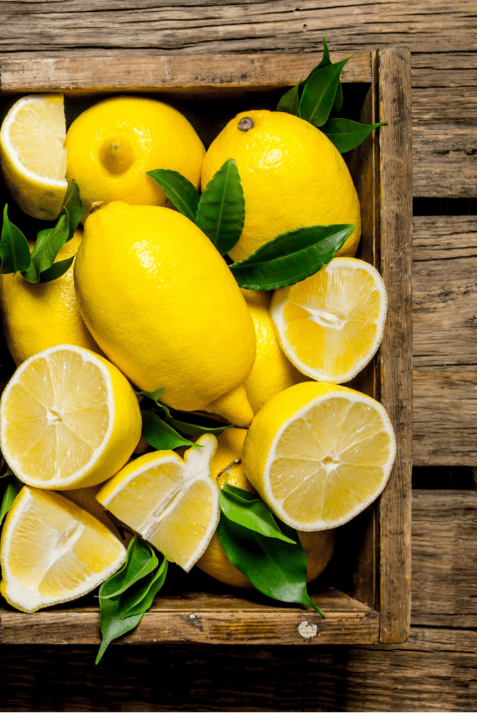 Whole and cut lemons in a wooden tray