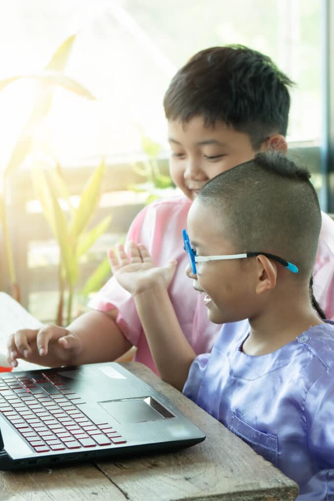 Two small boys in front of computer at library playing inline games