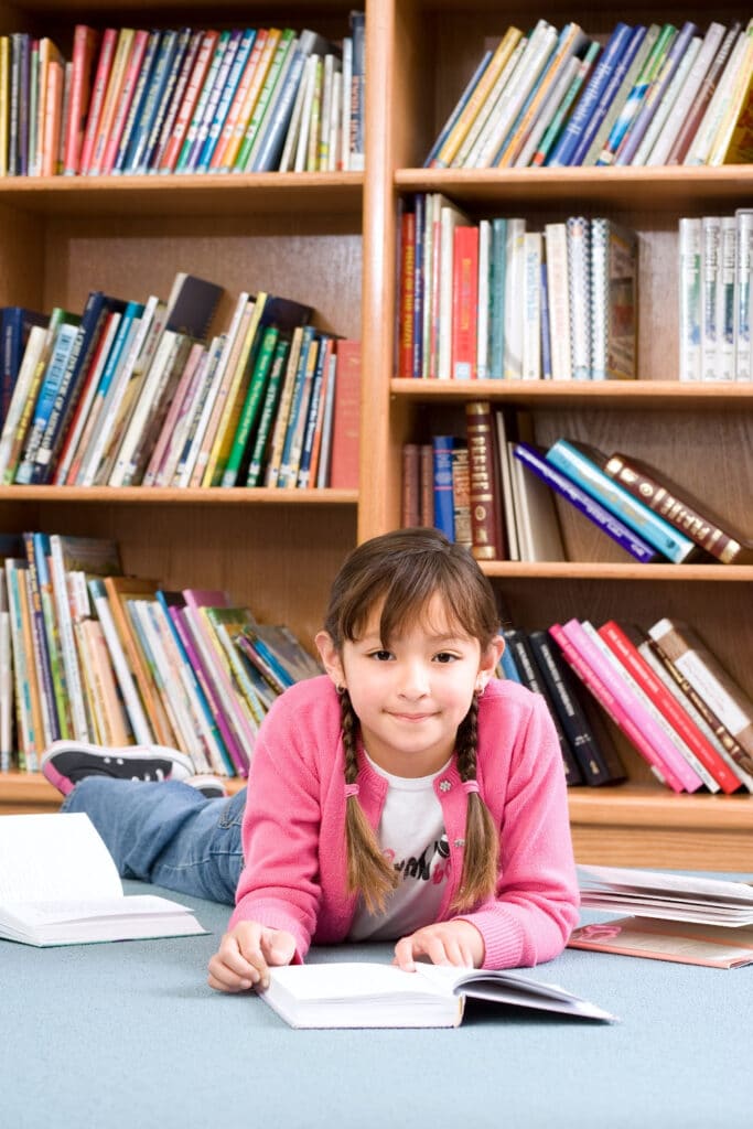 little girl at library reading a book