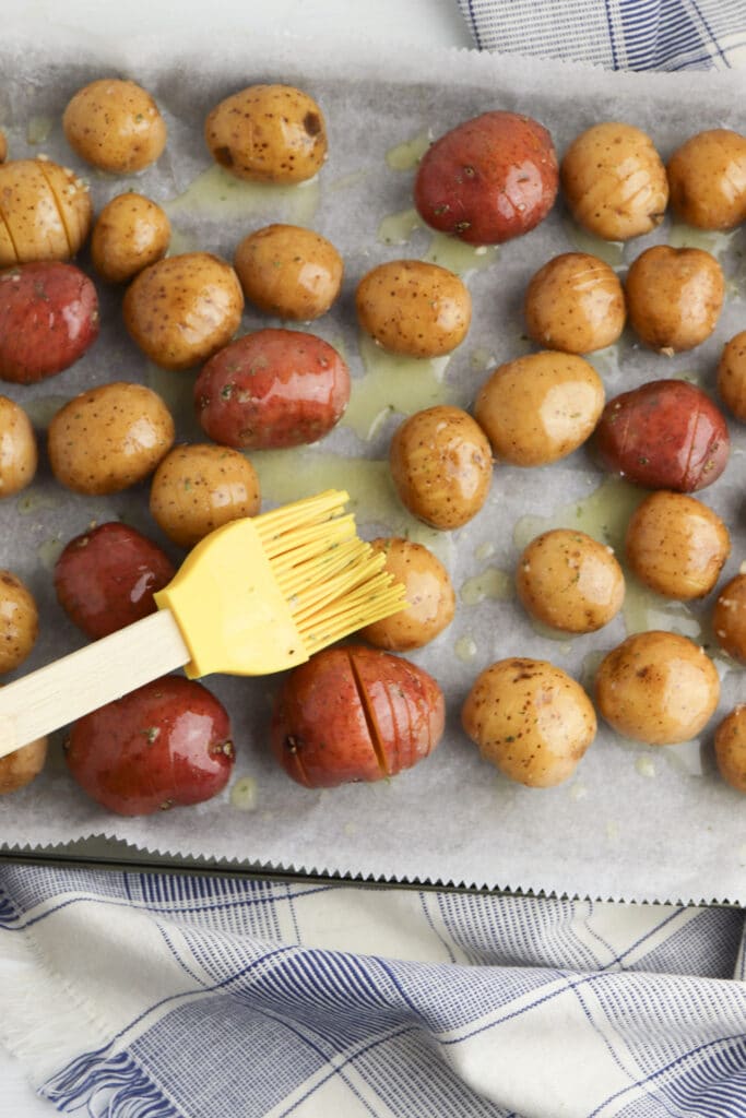 seasoning the potatoes on baking tray