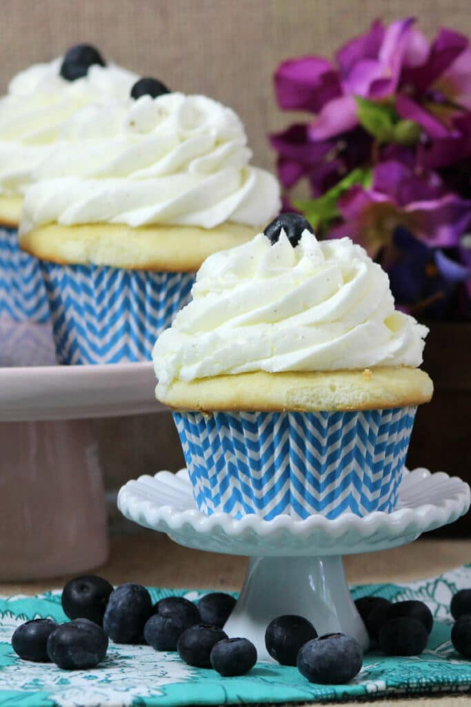 blueberry cupcakes with blue and white stripped cupcake paper on white stand