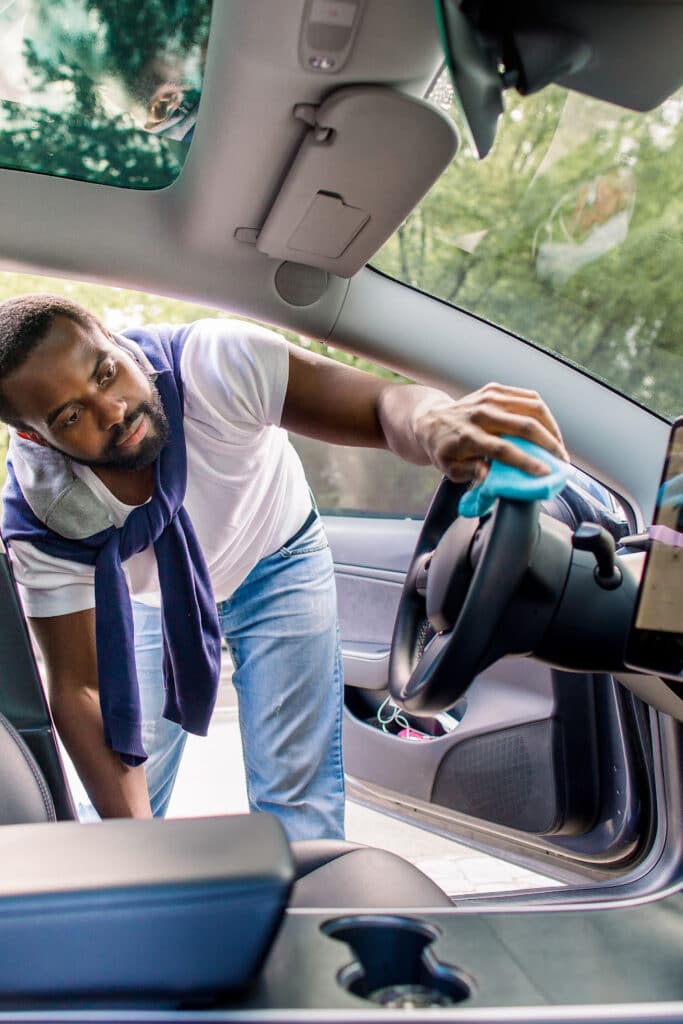 cleaning car interior - man wiping down steeling wheel with microfiber cloth