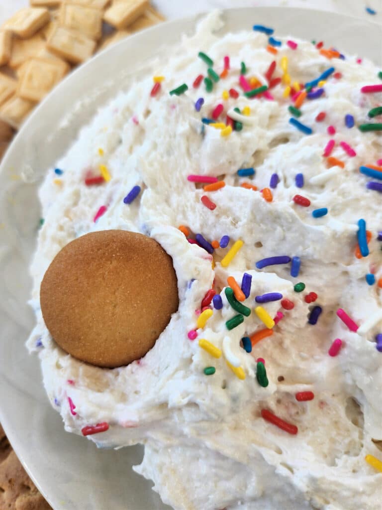 funfetti dip recipe in bowl with vanilla wafer and sprinkles