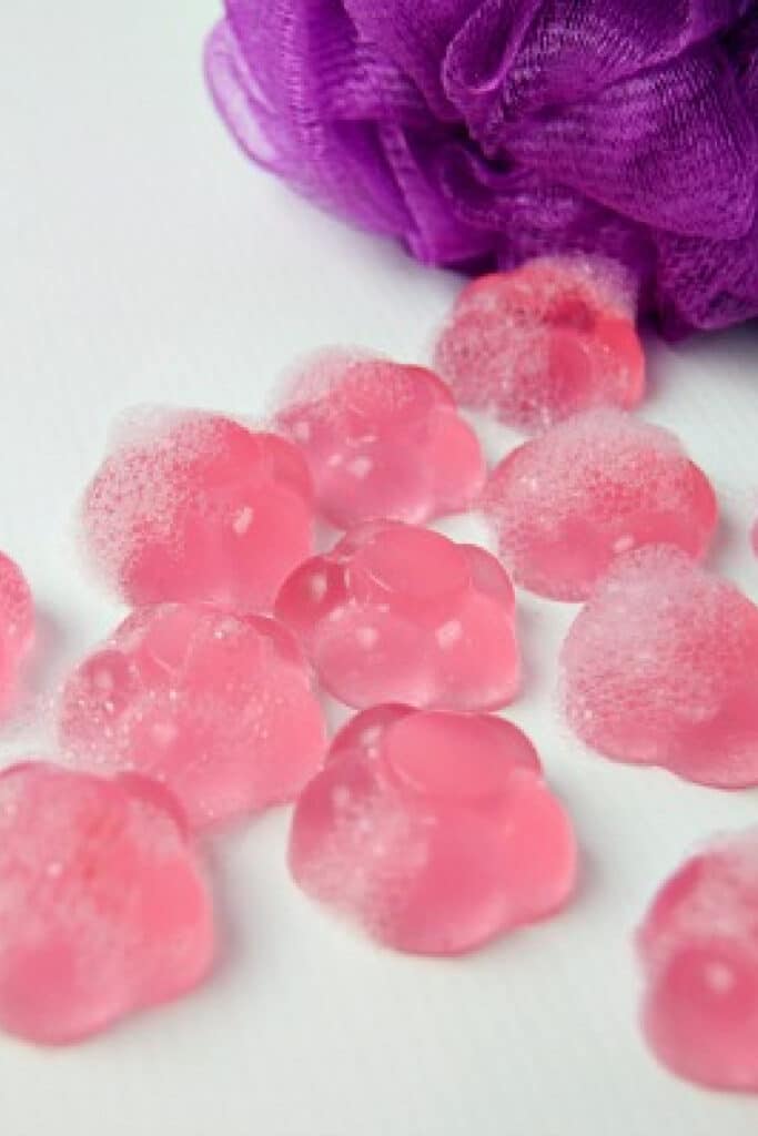 Shower jelly soap on white background with purple loofah sponge