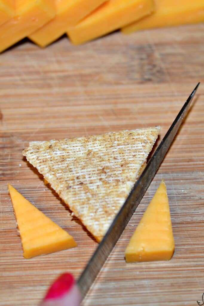 Cutting cheese on cutting board to make cracker pies