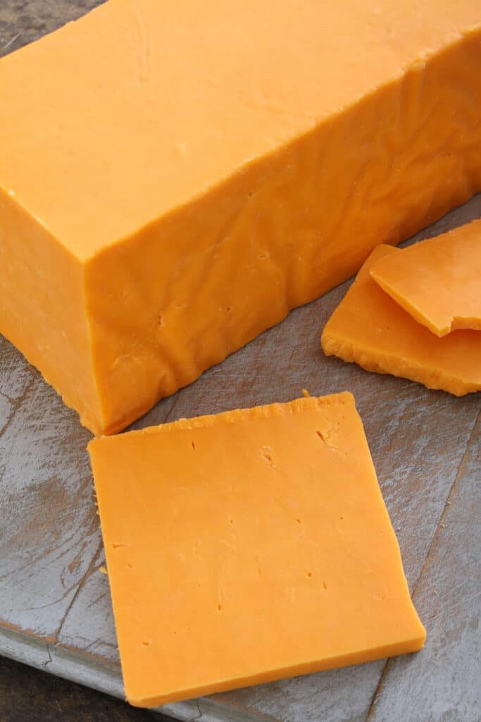 Sliced block cheddar Cheese on cutting board