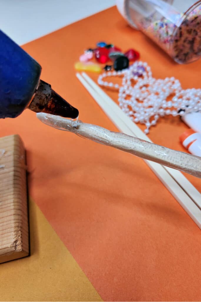 Adding hot glue to chop sticks