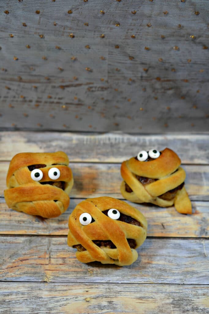 Cute Mummy meatballs with google eyes on wooden background