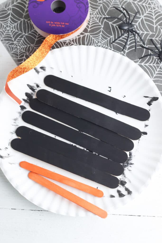 Painting popsicle sticks black for craft