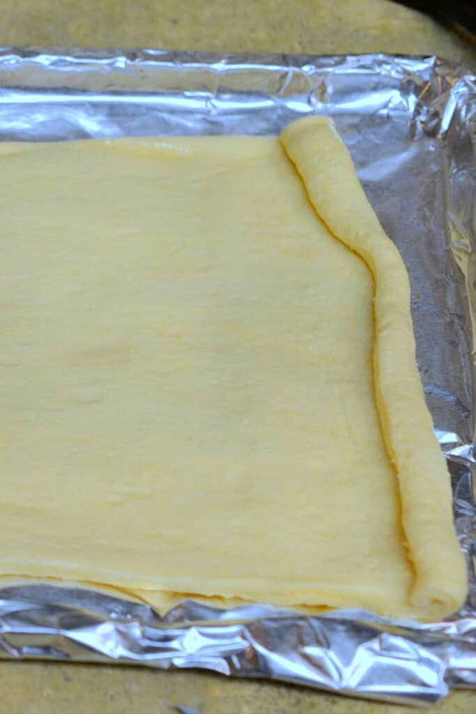 Rolling out dough on baking sheet lined with aluminum foil