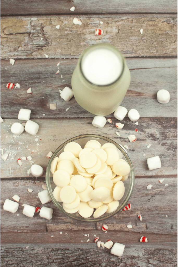 Ingredients for white hot chocolate. Pictured white chocolate chips, milk, mini marshmallows and crushed peppermint