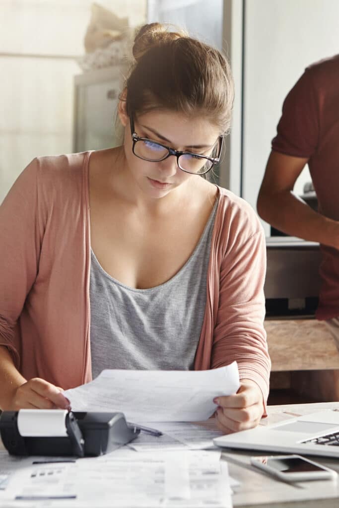 woman sitting at kitchen desk going through bills